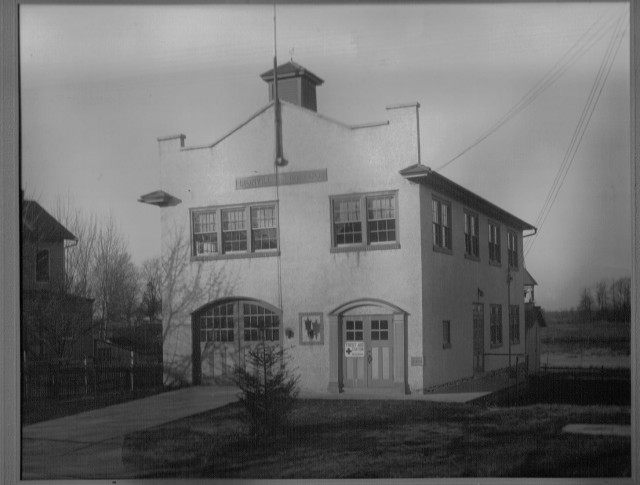 Photo of the 1929 firehouse taken in December 1933. The original wooden firehouse is visible in the right rear of the firehouse.